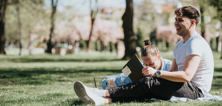 High school friends studying together, sharing smiles in a city parkの写真素材