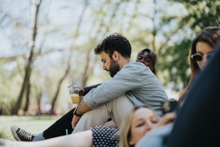 Friends relaxing together in a sunny park, enjoying a conversation and a drink
