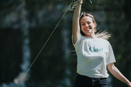 Joyful woman playing with a kite in a sunny park, embodying a carefree and happy moment outdoors