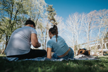 Students enjoying a sunny day outdoors, studying together in the parkの写真素材