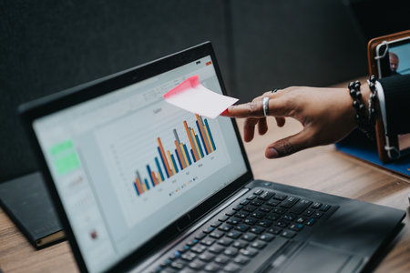 Business Professional Pointing at a Graph on Laptop Screen during a Meetingの写真素材