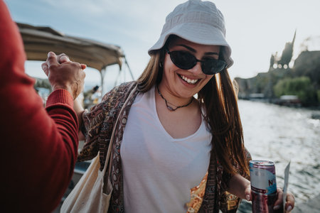 Close-up of friends holding drinks and enjoying a leisure day by the river with a backdrop of natureの写真素材
