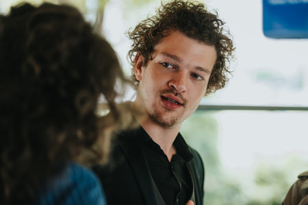 Young man with curly hair engaging in conversation in a relaxed indoor settingの写真素材