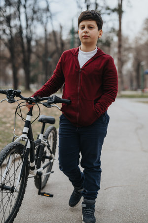 Young boy standing with his bicycle at the park, enjoying a day outdoorsの写真素材