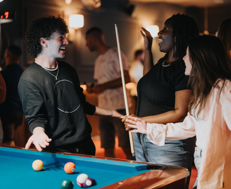 Joyful friends playing pool at a cozy bar during a fun night out togetherの写真素材