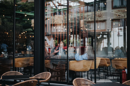 Group of friends enjoying coffee and conversation in a modern cafeの写真素材