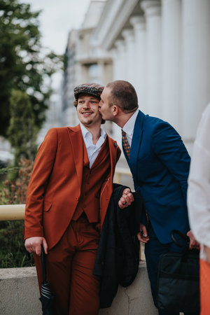 Gay business couple sharing a tender moment outdoors in a city setting