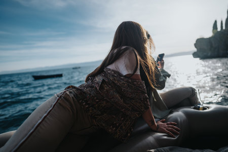 Young woman enjoys a peaceful boat ride on a sunny day, feeling joy and freedomの写真素材