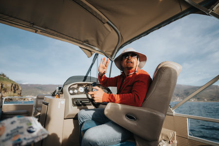 Man in a red sweater enjoying a relaxing boat ride on a sunny dayの写真素材