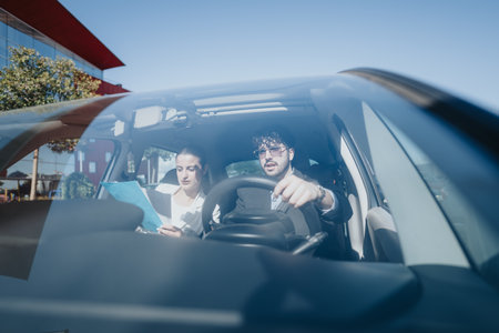Business colleagues reviewing documents in car during commuteの写真素材