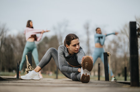 Active women engaged in outdoor fitness exercises in a park settingの写真素材