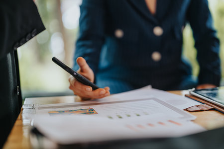 Business person holding smart phone while examining documentsの写真素材