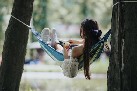 Young girl relaxing in a hammock in the park, enjoying a sunny dayの写真素材