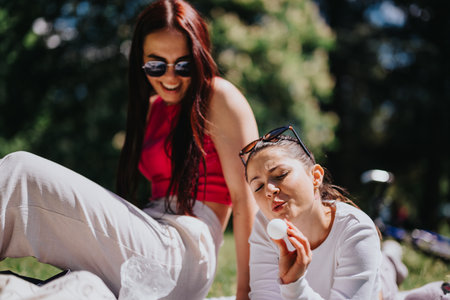 Friends enjoying a relaxed sunny day in the park, sharing laughs and casual moments togetherの写真素材