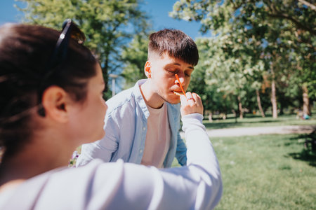 Young couple enjoying a sunny day in the park, woman playfully putting orange food in mans noseの写真素材