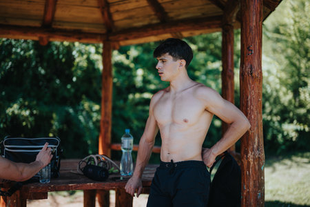 Young man taking a break after outdoor exercise in a wooden shelterの写真素材