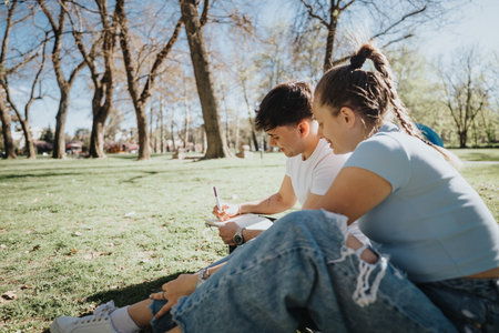 High school students studying together on campus grass, collaborating on a sunny day