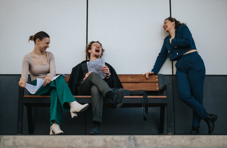 Colleagues sharing a laugh on a bench during a business meeting breakの写真素材