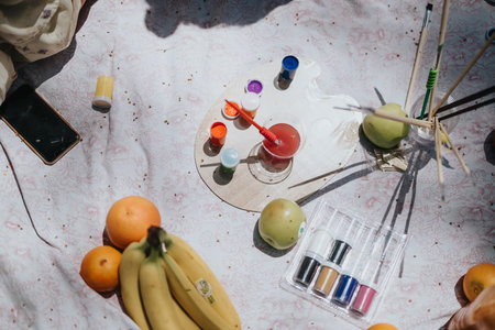 Overhead shot of creative painting session in the park with a sunny picnic setup.の写真素材
