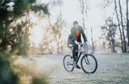 A blurred photo of a man enjoys a relaxed bicycle ride in a scenic park during a sunny afternoon, capturing the essence of freedom and enjoyment.の写真素材