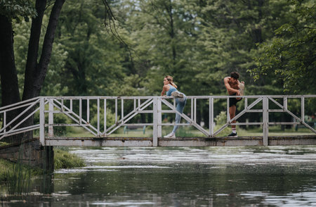 Fitness enthusiasts stretching on a bridge in a scenic park settingの写真素材