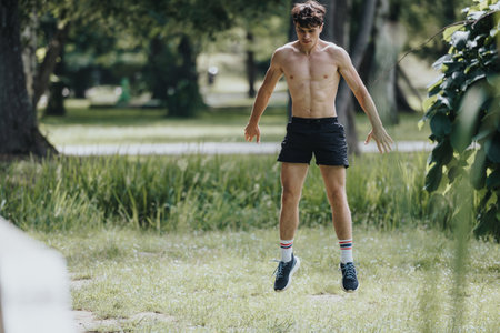 Fit young man doing outdoor exercises in a park on a sunny dayの写真素材