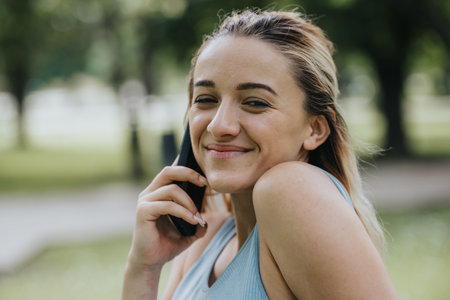 Happy woman talking on phone during outdoor fitness activity in park
