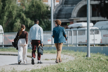 Young professionals walking together in an urban setting, engaging in conversationの写真素材