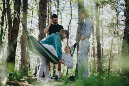 Group of friends enjoying relaxing time outdoors in a forest hammockの写真素材