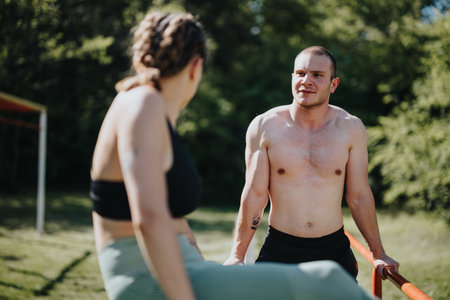 Two young athletes talking during an outdoor workout session in a park