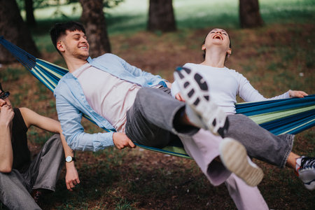 Friends relaxing on a hammock in the park, laughing and enjoying a sunny dayの写真素材