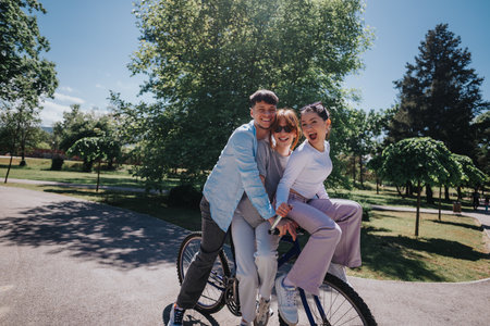 Three friends joyfully riding a bicycle together in a sunny park