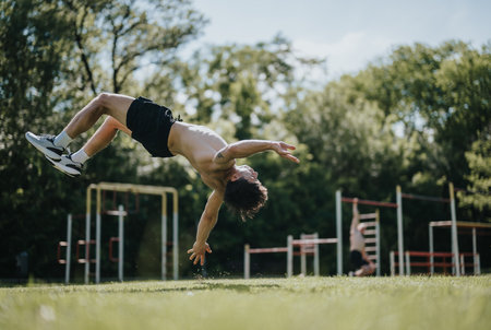 Athletic man doing a back flip at an outdoor park on a sunny day