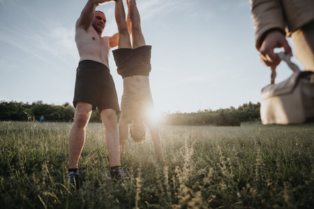 Friends exercising outdoors at sunset in a park, engaging in strength-building activitiesの写真素材