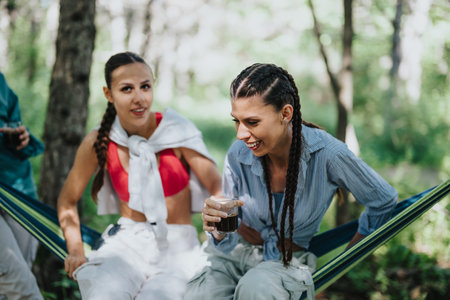 Young women enjoying coffee in a hammock in the forest on a sunny dayの写真素材