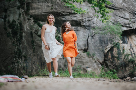 Two young women enjoying nature walk together near rocky cliffの写真素材