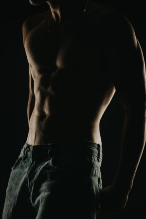 Strong and muscular male torso in shadows conveying strength and fitnessの写真素材