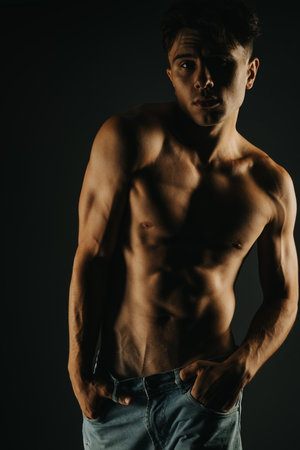 Portrait of a shirtless young man showcasing muscular physique in jeans