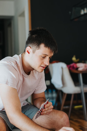 Young man enjoying a game of cards at home in a relaxed settingの写真素材