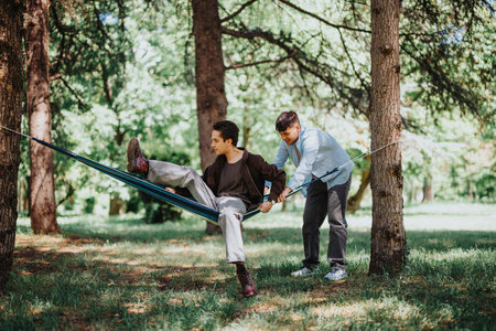 Young men enjoying a playful moment with a slack-line in a sunny parkの写真素材