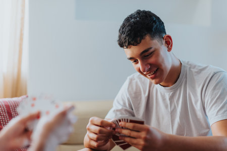 Young man enjoying a card game with friends or family at homeの写真素材