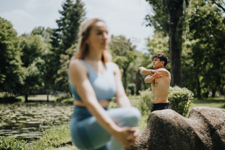 Two people doing warm up exercises and calisthenics in a peaceful park settingの写真素材