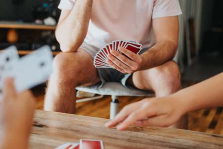 Friends having fun playing cards at home in a cozy settingの写真素材