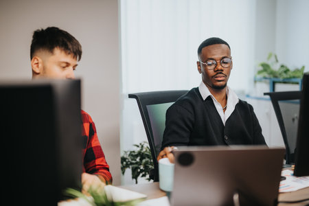 Diverse business team working at office desks, analyzing documents and using computersの写真素材