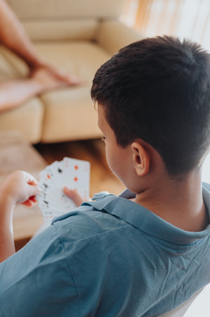 Young boy playing cards at home with family during a cozy afternoonの写真素材