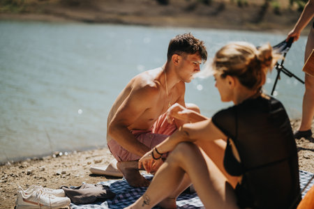 Friends enjoying a sunny picnic by the lake in natureの写真素材