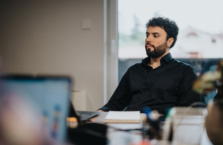 Business professional in meeting room contemplates during a presentationの写真素材