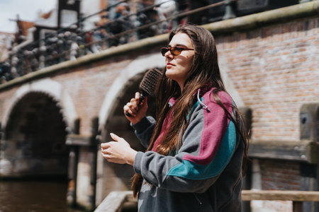 Young woman enjoying a sunny day in Amsterdam by the canal with historic buildings in the background
