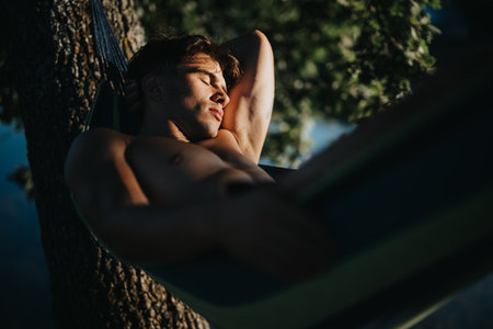 Man relaxing on hammock enjoying summer in nature under the sunの写真素材