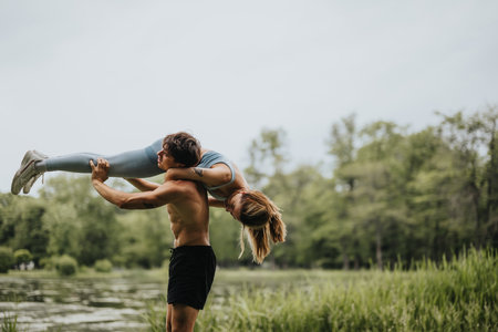 Man lifting his female partner outdoors showcasing fitness and strengthの写真素材
